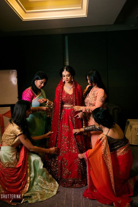 Stunning bride in red lehenga getting ready with bride