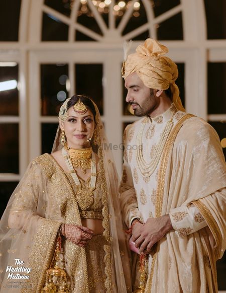 Matching bride and groom in ivory and gold outfits 