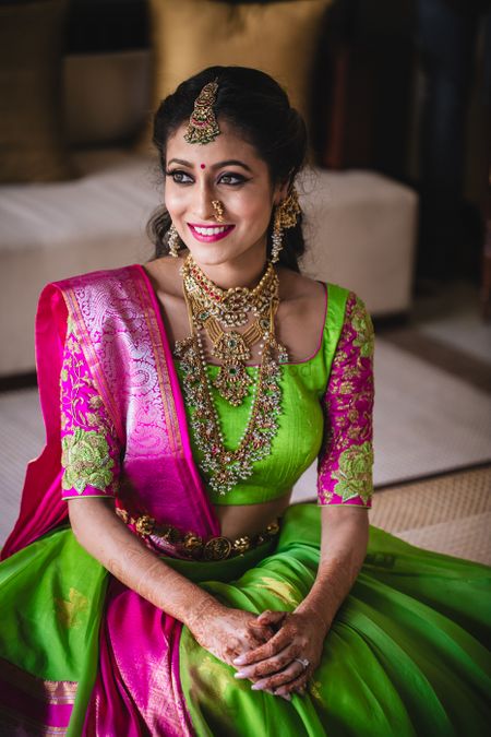 Mehendi bridal portrait in green and pink lehenga and layered jewellery