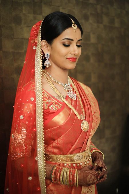 South Indian bride in orange and gold with simple jewellery 
