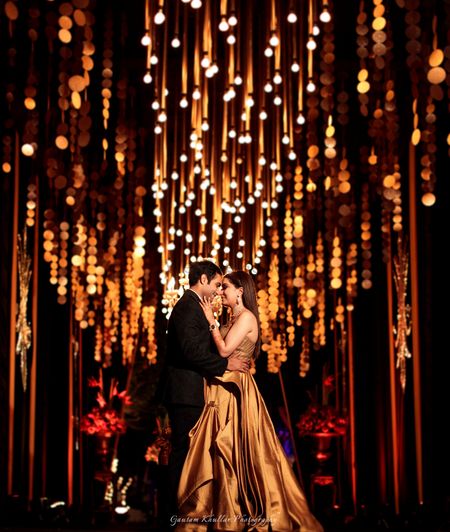 Photo of Beautiful couple shot on sangeet with gold decor