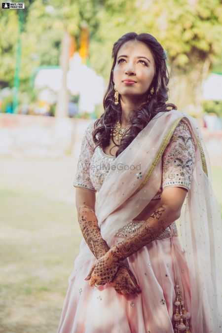 A bride in a liglht pink lehenga on her mehendi day
