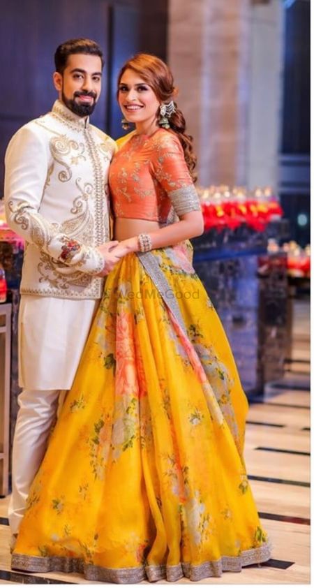 Photo of A bride and groom pose on their mehendi day