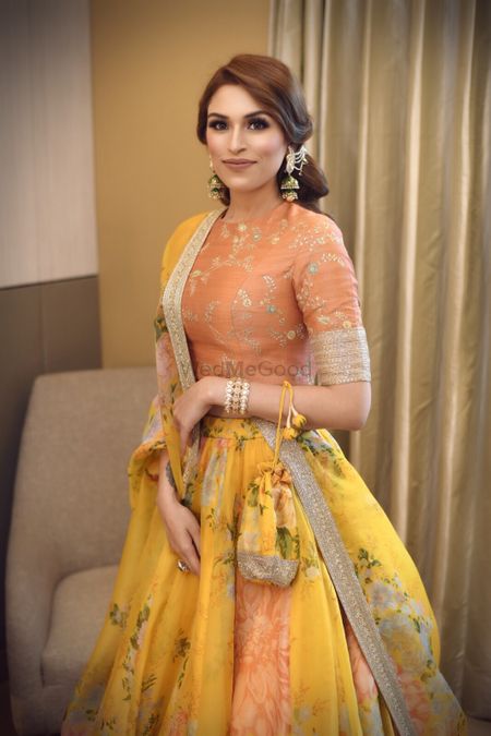 A bride poses in a coral and yellow light lehenga 