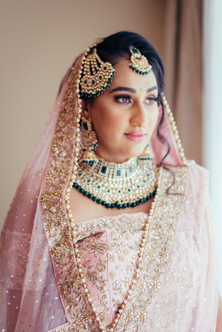 Contrasting jewellery with green beads with pastel lehenga 