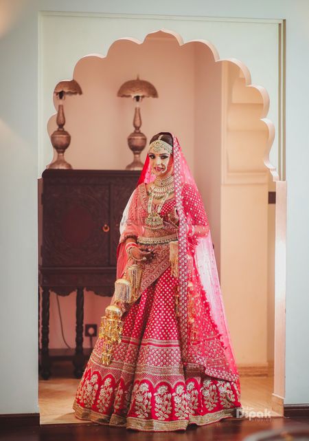 Bride in red and gold bridal lehenga with floral motifs 