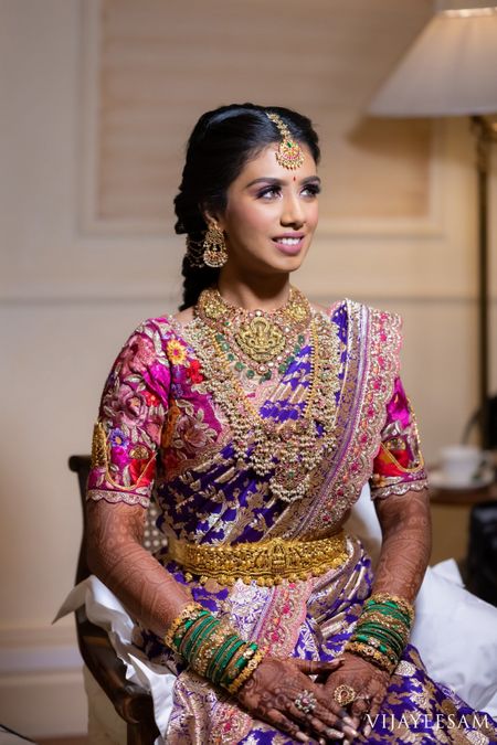 South Indian bride wearing an aubergine and gold saree with a multi-coloured blouse.