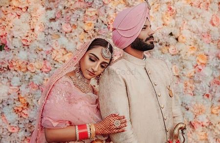 Photo of Sikh wedding couple shot with floral backdrop