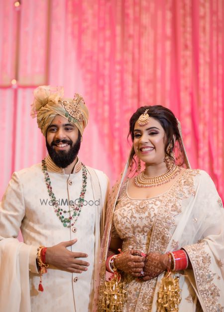 Photo of Coordinated bride and groom in white outfits