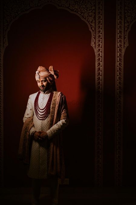 Groom dressed in an ivory sherwani with pastel peach stole.
