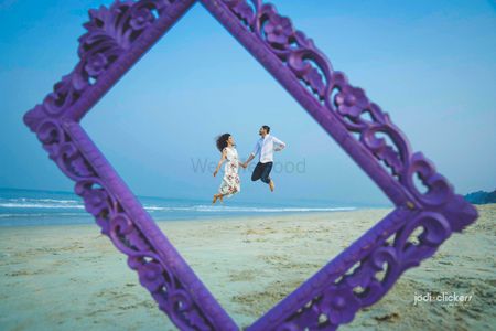 Photo of Beach pre wedding shoot with frame prop