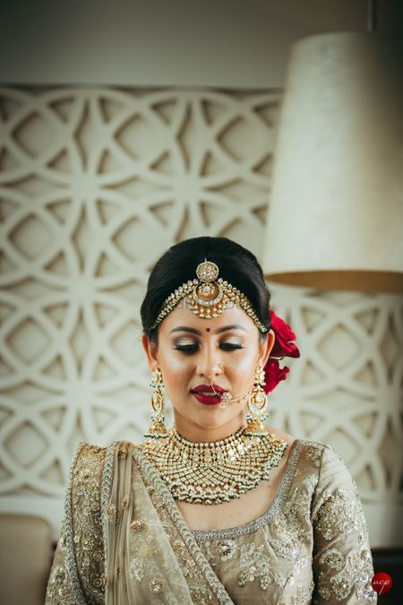 Contrasting makeup and bridal bun in red with gold lehenga 