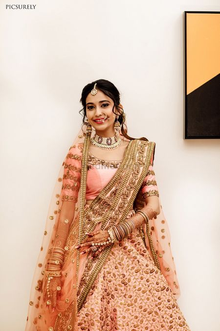 A bride in pink lehenga and scalloped dupatta
