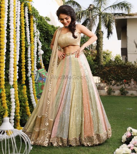 A bride to be in a sorbet-colored outfit for her mehndi 