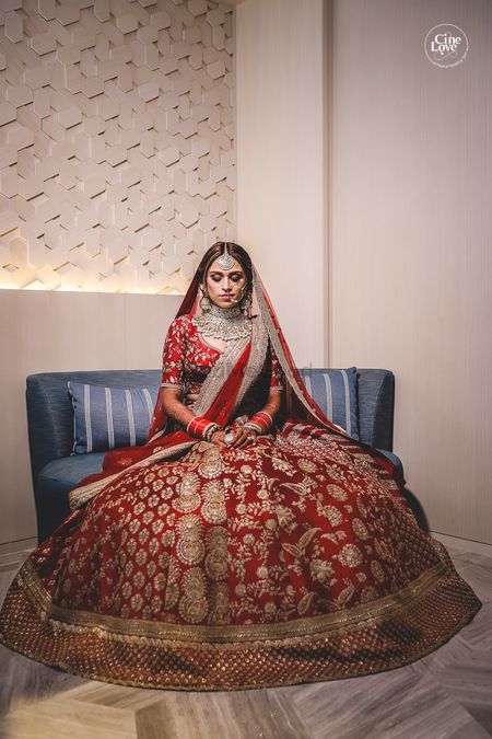 Photo of Bride in deep red and gold lehenga with panels