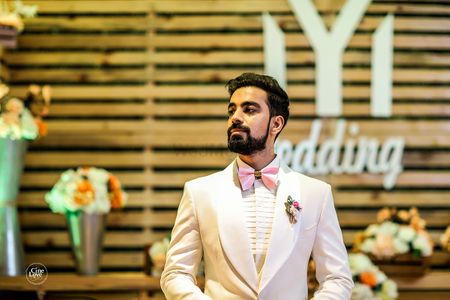 Quirky groom with light pink bow tie white suit 