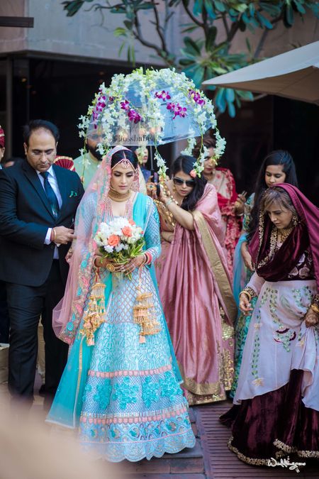 Bridal entry with a floral umbrella in offbeat blue lehenga 