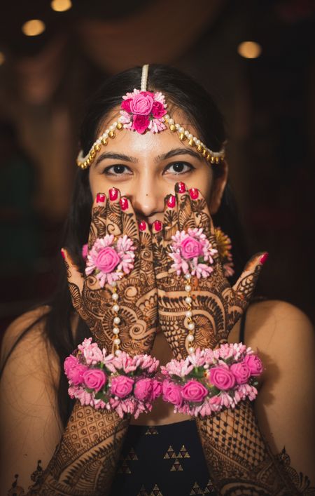 Pretty bride on her mehendi wearing pink floral jewellery