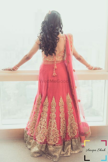 Bride wearing Gold and Pink Lehenga against window