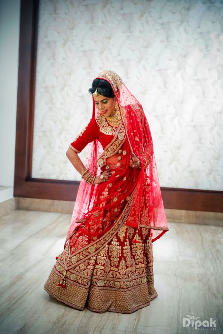 Bride Posing in Bright Red and Gold Bridal Lehenga