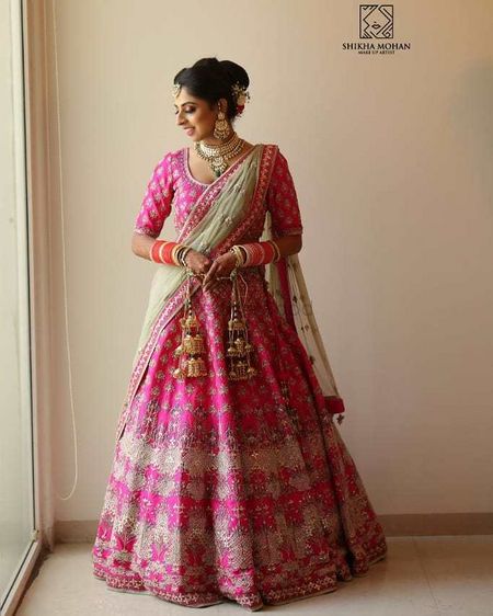 A bride in a pink lehenga with a contrasting mint dupatta 