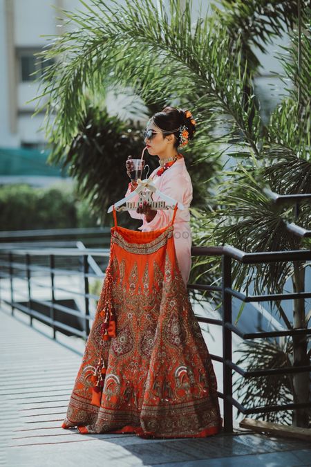 Bride holding lehenga and having a drink 