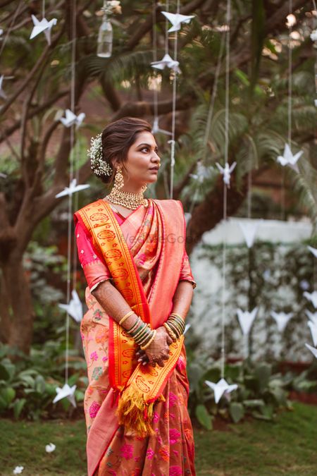 Bride in orange saree against paper decor 