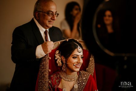Bride getting ready with father placing dupatta on her head 