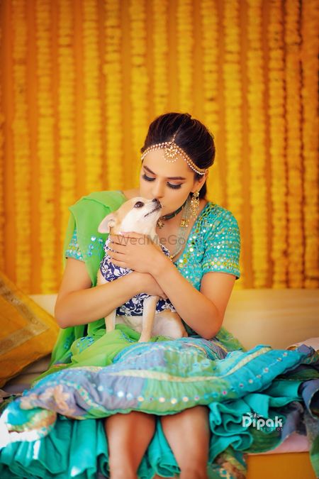 Photo of Bride in green mehendi lehenga kissing her dog