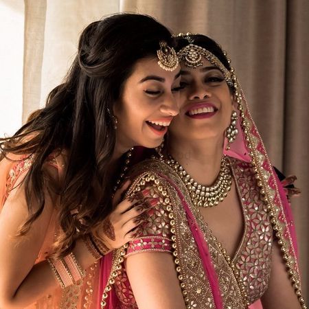Photo of A bride all decked up for her big day laughing with her sister