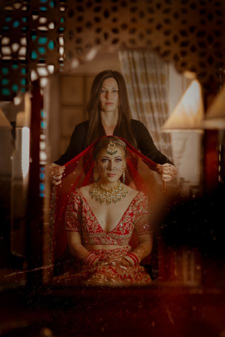 Bride in red with dupatta placing on head shot 