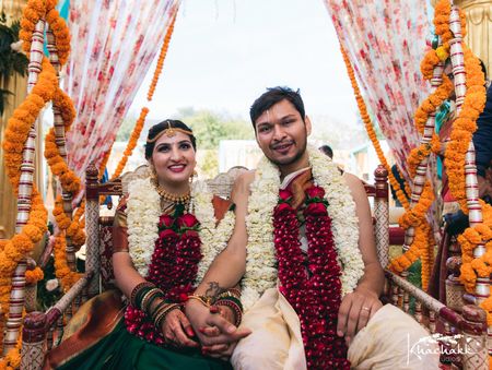 A south Indian couple wearing heavy rose jaimala
