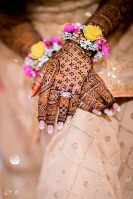 Bridal hands with mehendi and engagement ring with floral jewellery