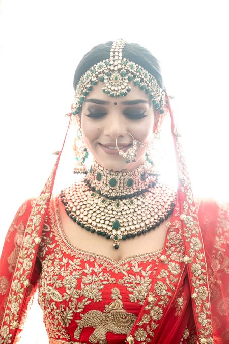 Photo of Contrasting green jewellery with red lehenga for north indian bride
