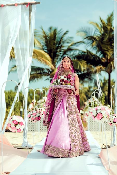 Bridal entry in light pink lehenga holding bouquet