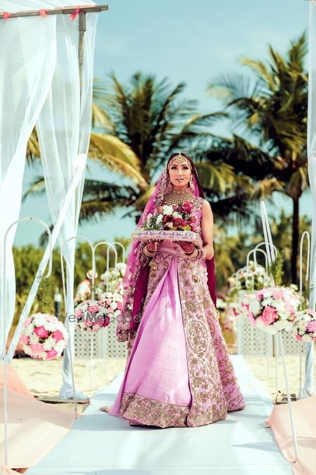 Photo of Bridal entry in light pink lehenga holding bouquet