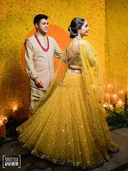 A couple coordinating in yellow and creme on their mehendi ceremony