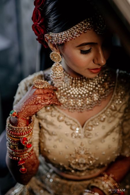 A bride in a gold lehenga and stunning jewelry on her wedding day