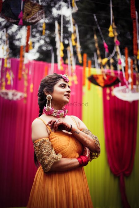 Bride on mehendi in orange outfit and choker 