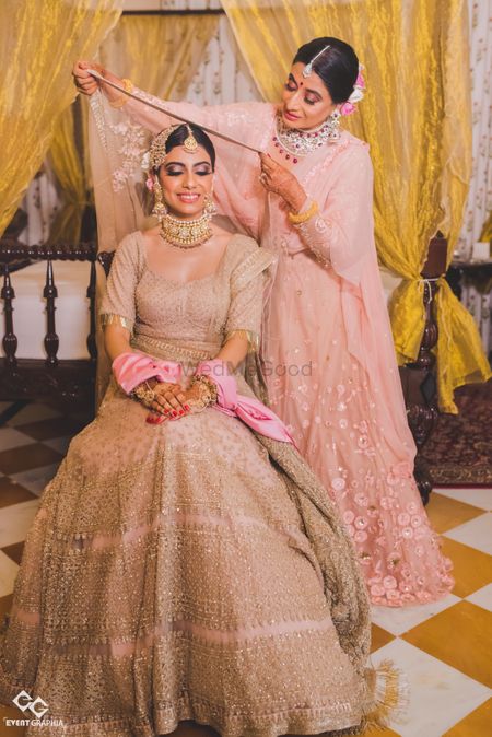 Bride with sister placing dupatta on her head 