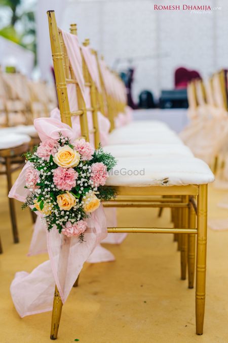 Neat, and pretty floral decoration pn chairs at a wedding