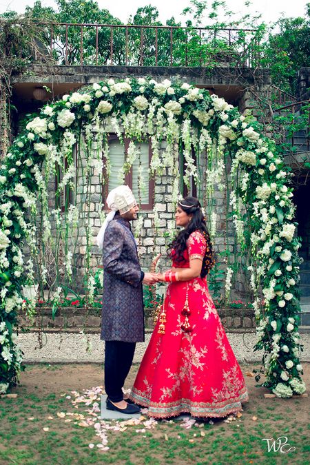 A couple holding hands infront of a giant floral wreath
