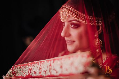 Bride holding her red dupatta as a veil
