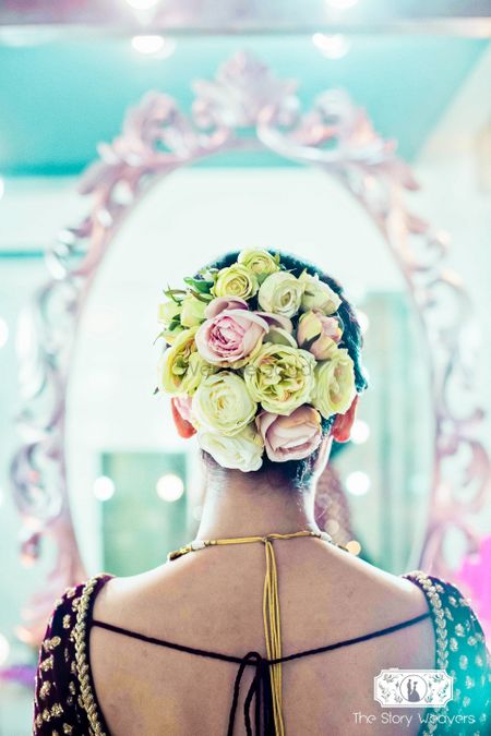 Unique bridal bun with big yellow and pink roses contrasting with dupatta