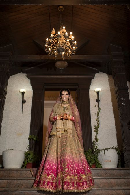 A beautiful bride in gold lehenga with a subtle mix of pink ombre in it.
