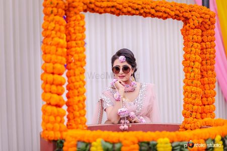 Bride on mehendi wearing sunglasses behind floral frame 