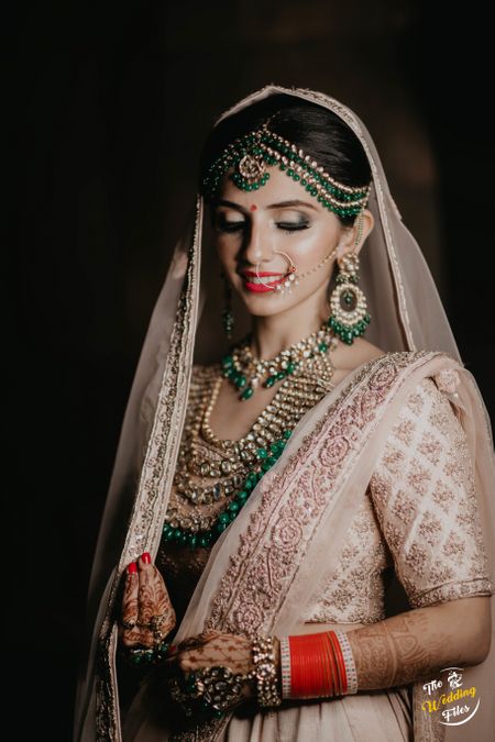 Contrasting unique bridal jewellery with green beads with pastel lehenga