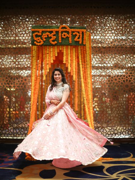 A bride to be in a shimmery pink lehenga twirling on her mehndi day