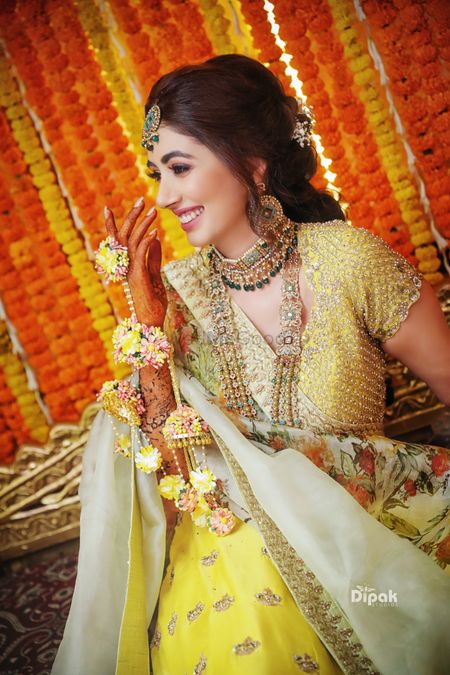 A bride-to-be wearing matching yellow floral kaleere with her yellow mehndi lehenga
