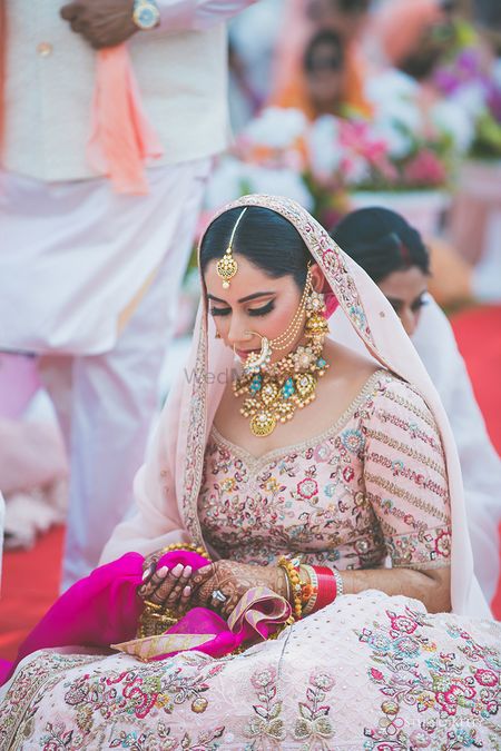 A sikh bride in a pink lehenga with contrasting blue jewellery